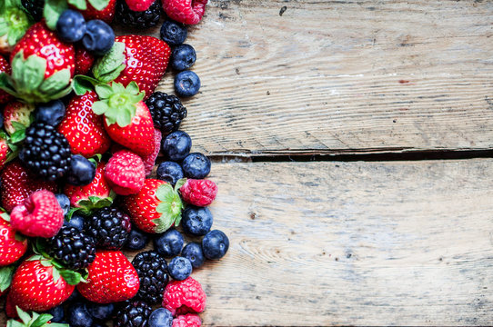 Mix of berries on rustic wooden background