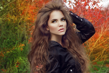 Beautiful brunette model woman posing with long wavy hair at col