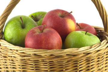 Ripe green and red apples in brown wicker basket isolated