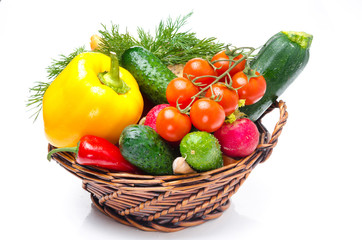 assorted fresh vegetables and herbs in a basket on white