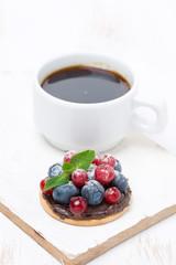 mini cake with chocolate cream and berries and a cup of coffee