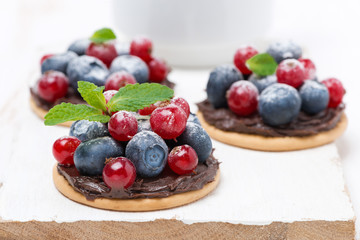 mini cakes with chocolate cream and berries on a white board
