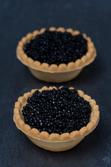 tartlets with black caviar on a dark background