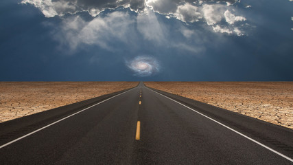 Road leads into desert toward galaxy above horizon