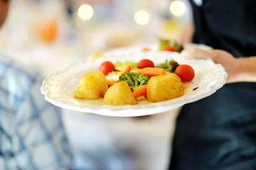 Waitress carrying a plate with veggie dish