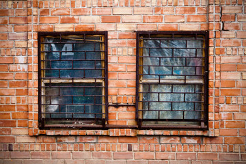 two windows with bars on the brick wall