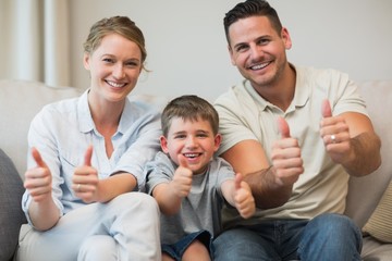 Family gesturing thumbs up on sofa