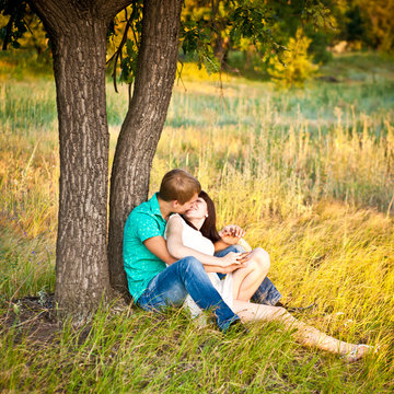young couple kissing under a tree