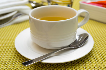 Cup of tea on saucer with a spoon
