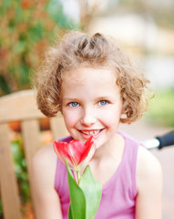 Mädchen lächelt mit roter Tulpe