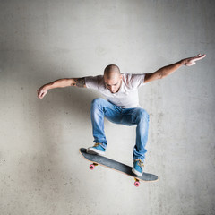 Skateboarder jumping against concrete wall.