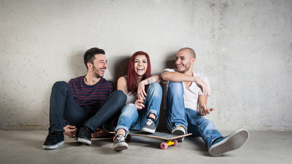 Happy friends portrait with skateboard against concrete wall. - obrazy, fototapety, plakaty