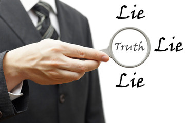 truth and lie concept with businessman holding magnifying glass