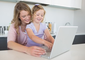 Fototapeta na wymiar Mother assisting daughter in using laptop at table