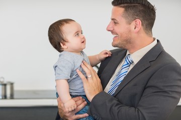 Businessman looking at baby boy in kitchen