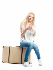 Blondes Mädchen auf Koffer simst mit Handy © von Lieres