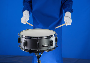 Drum and drumsticks in hand on blue background