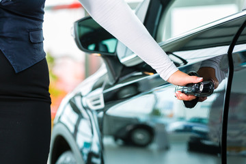 Young woman with auto in car dealership