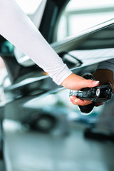 Young woman with auto in car dealership