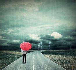 Lonesome man with red umbrella on a road in bad weather