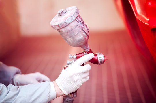 Worker Painting A Red Car In Paiting Booth