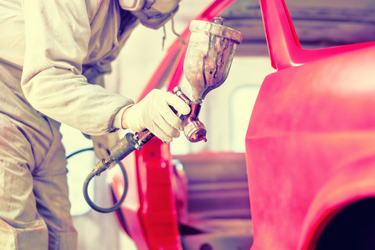 Professional Worker Spraying Red Paint On A Car Body