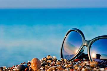 sunglasses lying on the beach on the wet pebbles
