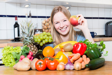 Junge frau sitzt vor einem Berg Gemüse und Obst