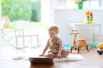Cute blonde little toddler girl playing with notebook