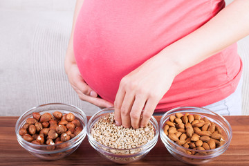 Healthy pregnancy. Pregnant woman eating different seeds