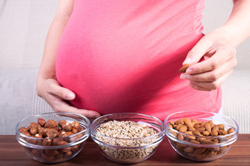 Healthy pregnancy. Pregnant woman eating different seeds