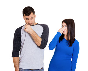 Woman smells bad odor looking at man who sniffs himself