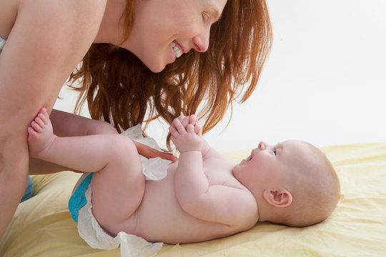 Baby With Mother Diapering And Playing Smiling