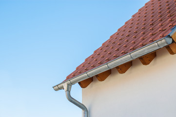 Corner of the house with tile roof on a background of blue sky
