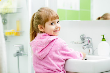 child girl washing her face and hands in bathroom