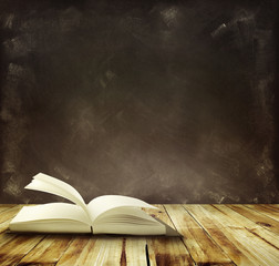 One book on table in front of black board background