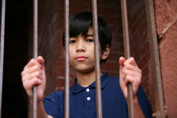 Boy standing behind bars