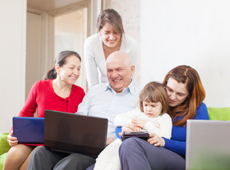 Happy multigeneration family uses few portable electronic commun