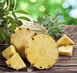 Pineapple with slices on a wooden table.