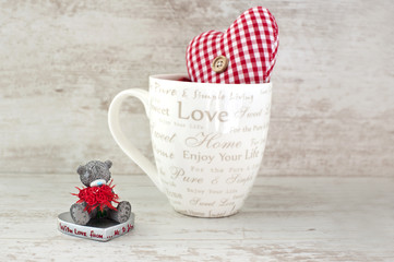 Valentine miniature teddy bear and red heart on wooden backgroun