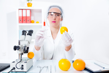 Young female scientist injecting GMO into lemon in laboratory