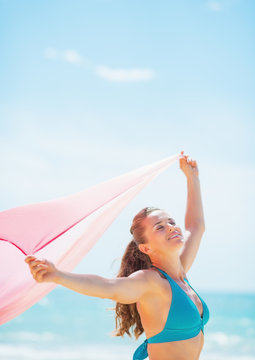 Happy young woman with parero rejoicing on beach