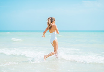 Fototapeta na wymiar Young woman in swimsuit running into sea