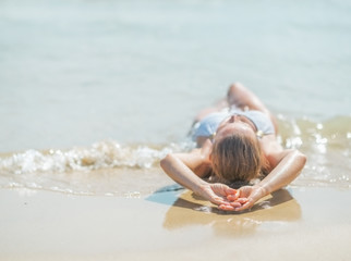 Young woman in swimsuit laying on sea shore. rear view