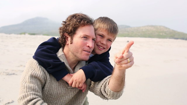Man piggybacking his son at beach
