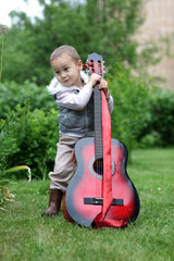 Fototapeta premium little boy with guitar outdoors