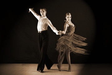 dancers in ballroom against on black