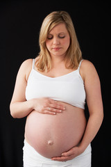 Portrait Of 9 months Pregnant Woman Wearing White On Black Backg