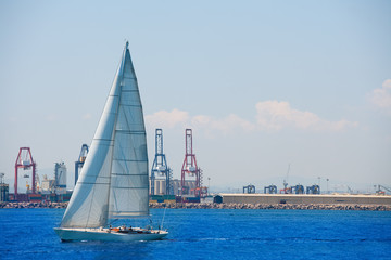 Valencia city port with sailboat and cranes in background