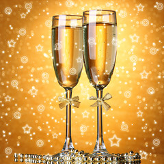 Two glasses of champagne on bright background with lights
